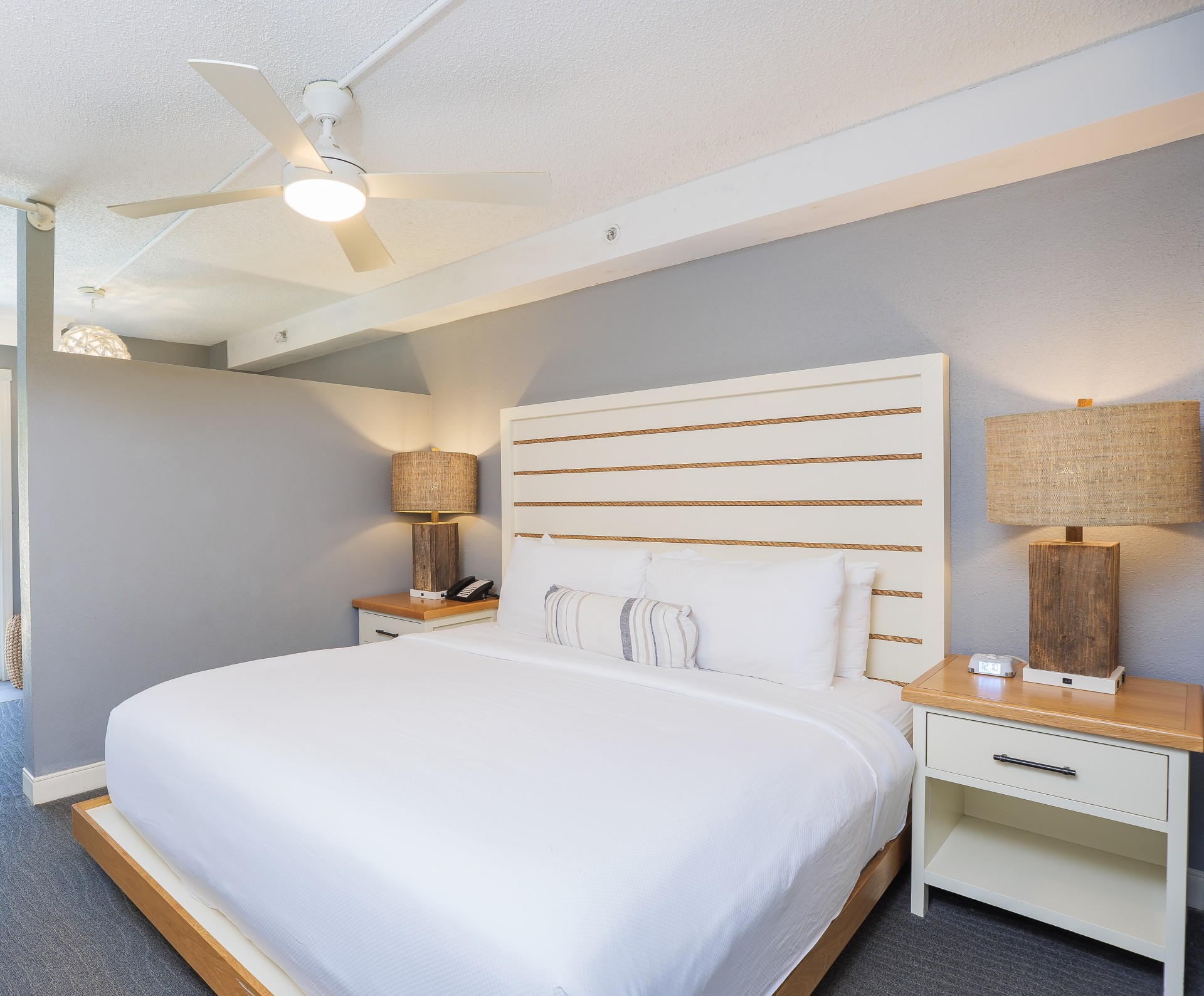 a bed with a white bedding and a white ceiling fan
