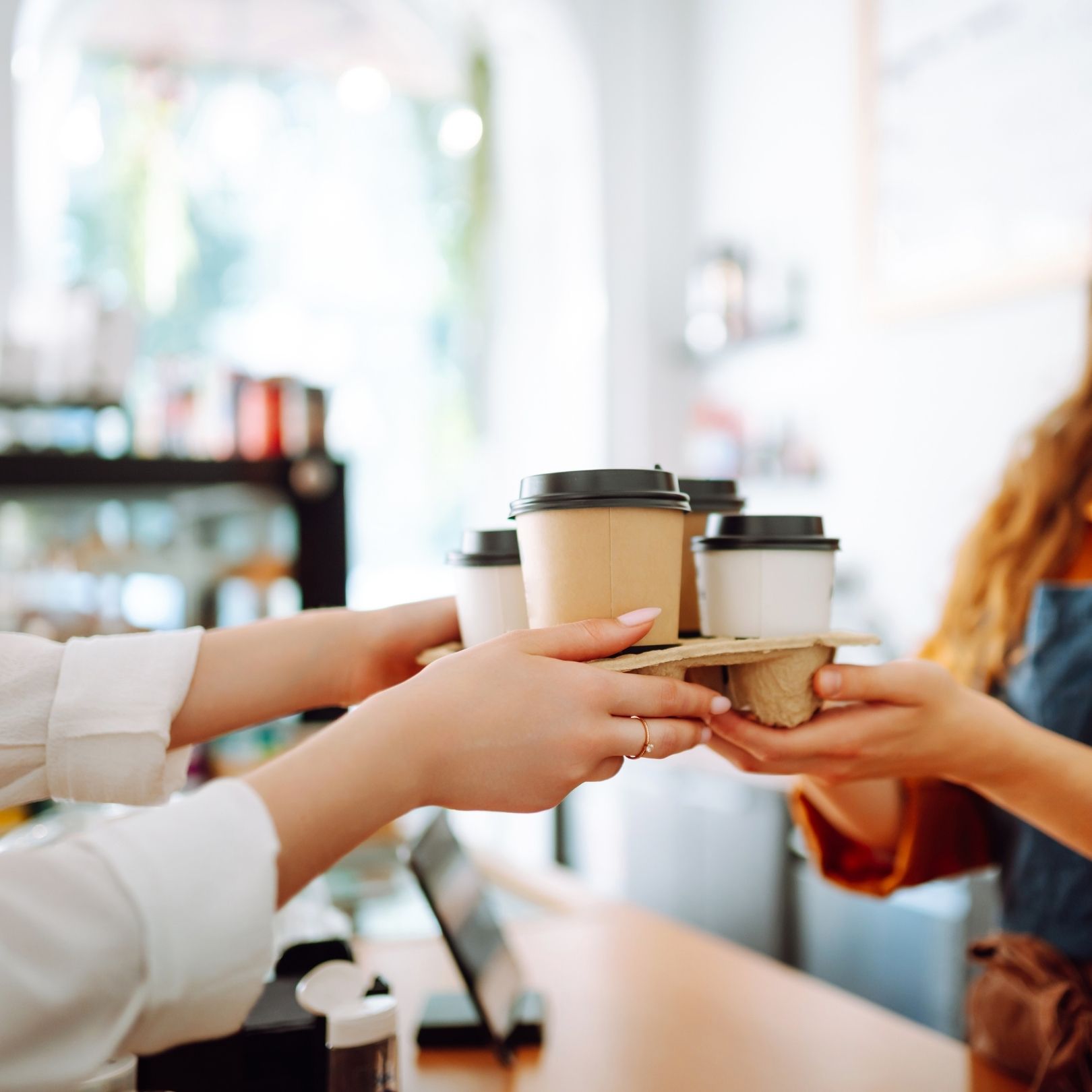 a woman handing a tray of coffee to a customer