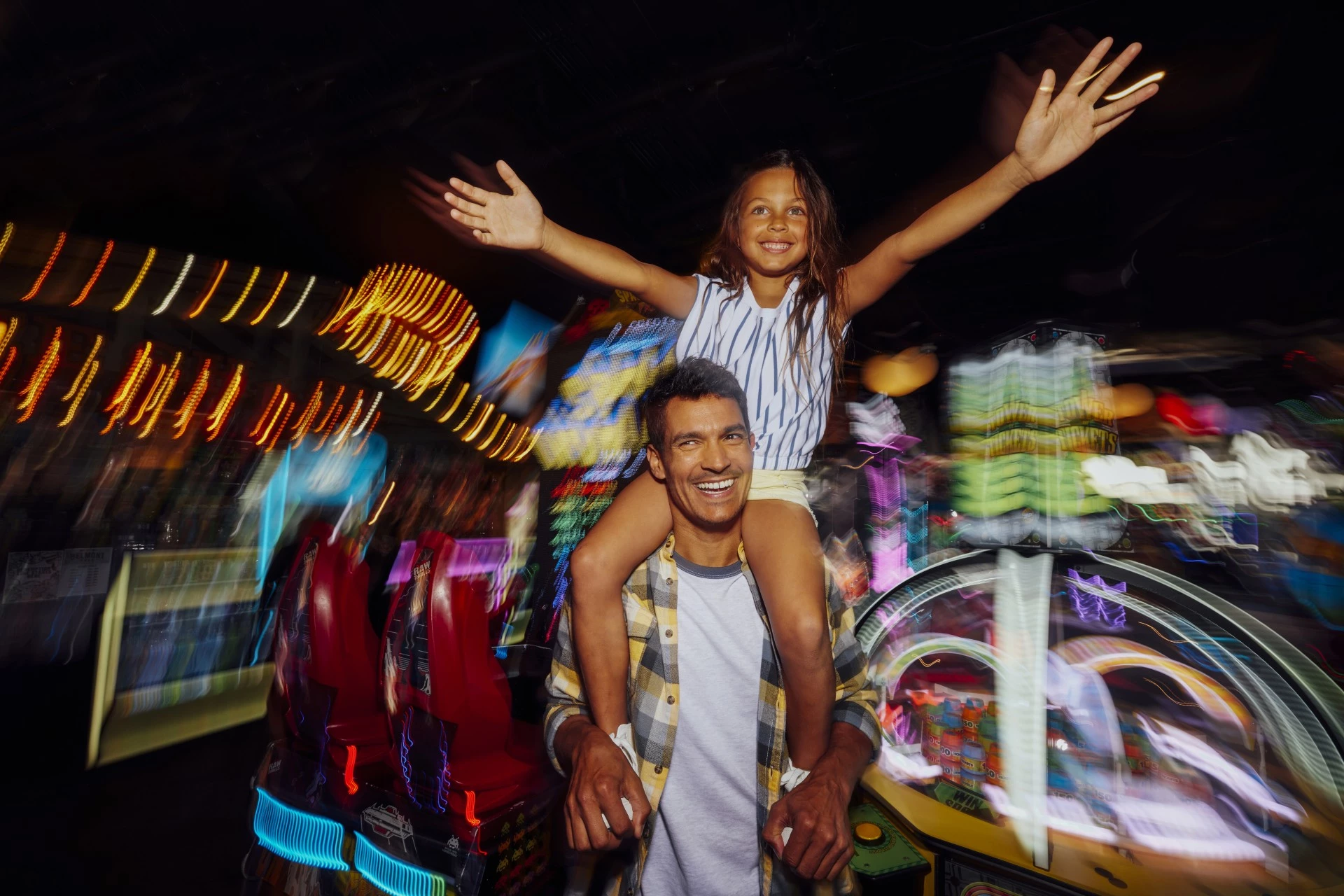 a man carrying a girl on his shoulders at the arcade