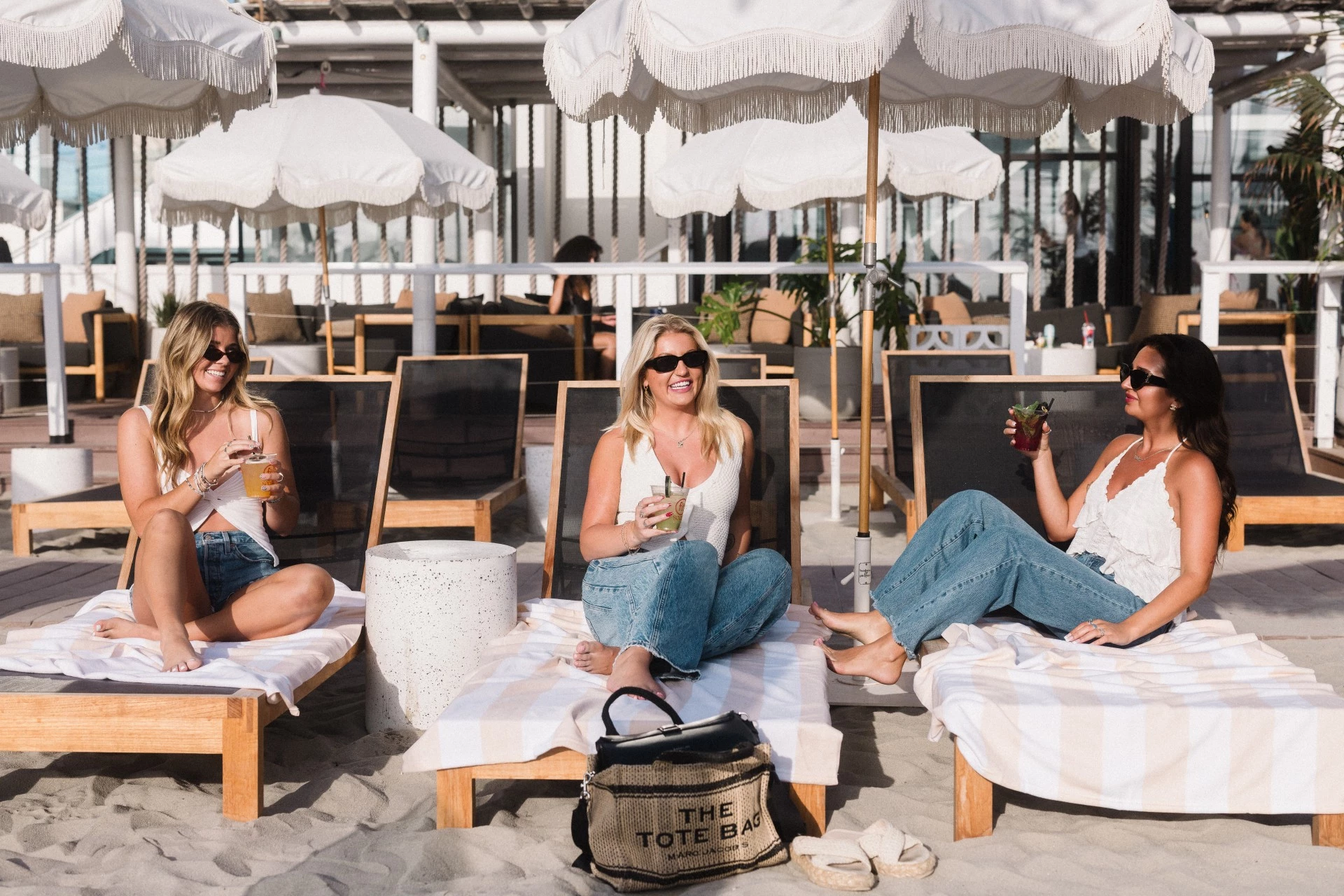 a group of women sitting on lounge chairs under umbrellas