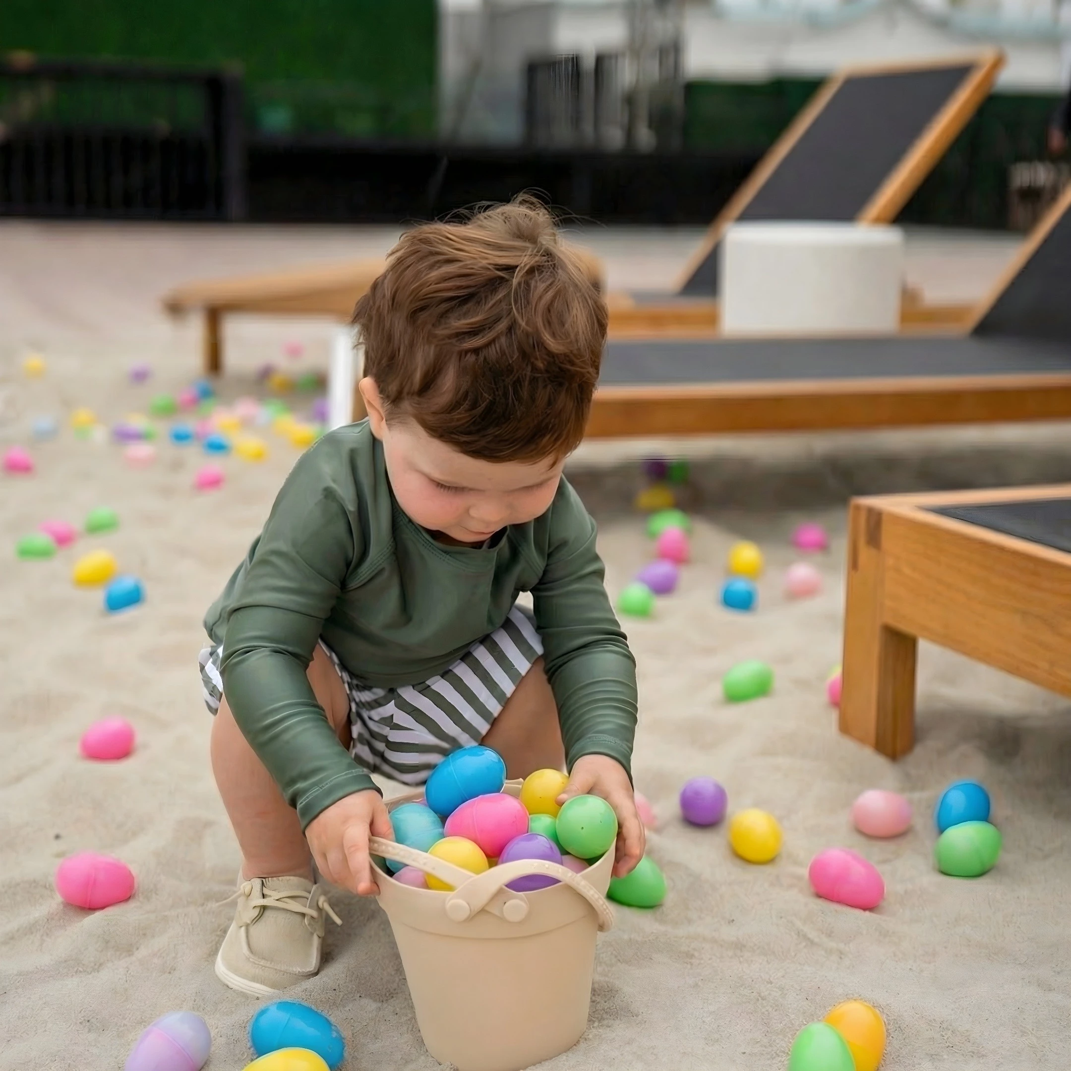 a baby playing with a bucket of eggs