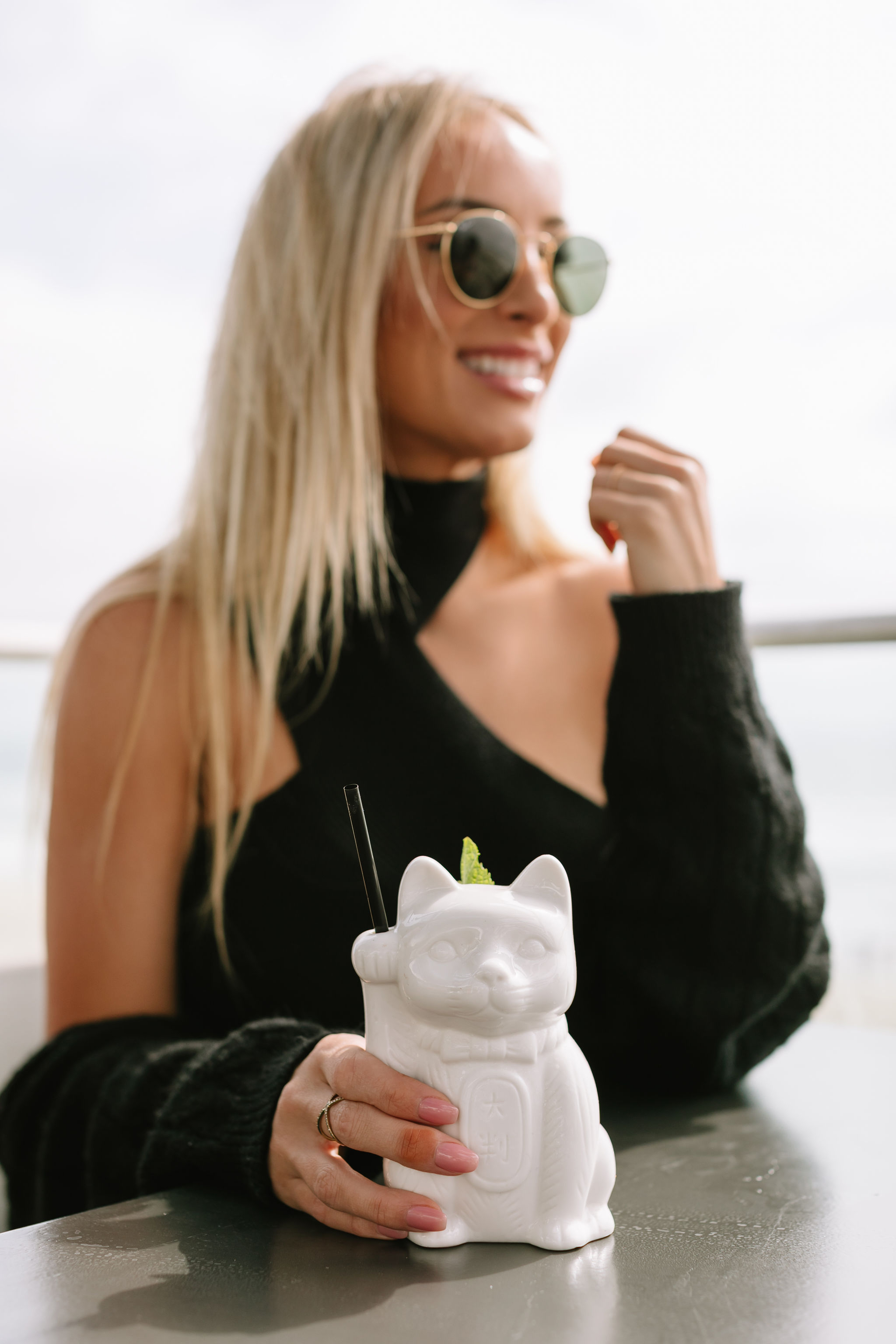 a woman holding a white cat shaped drink container