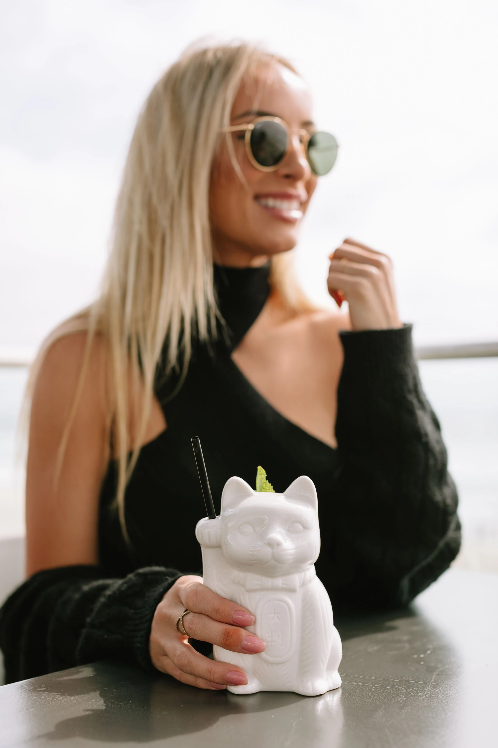 a woman holding a white cat shaped drink container