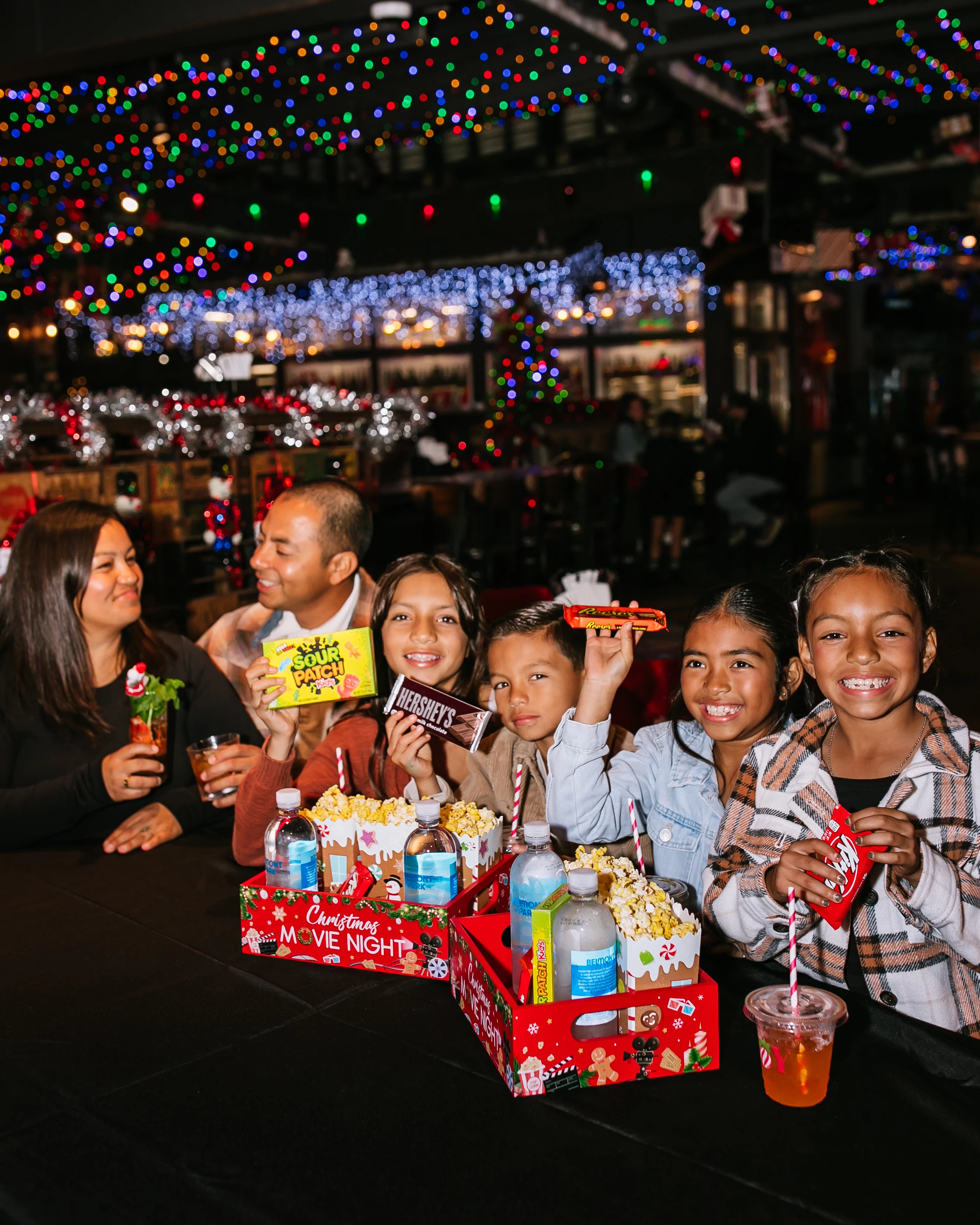 a group of people sitting at a table with food and drinks