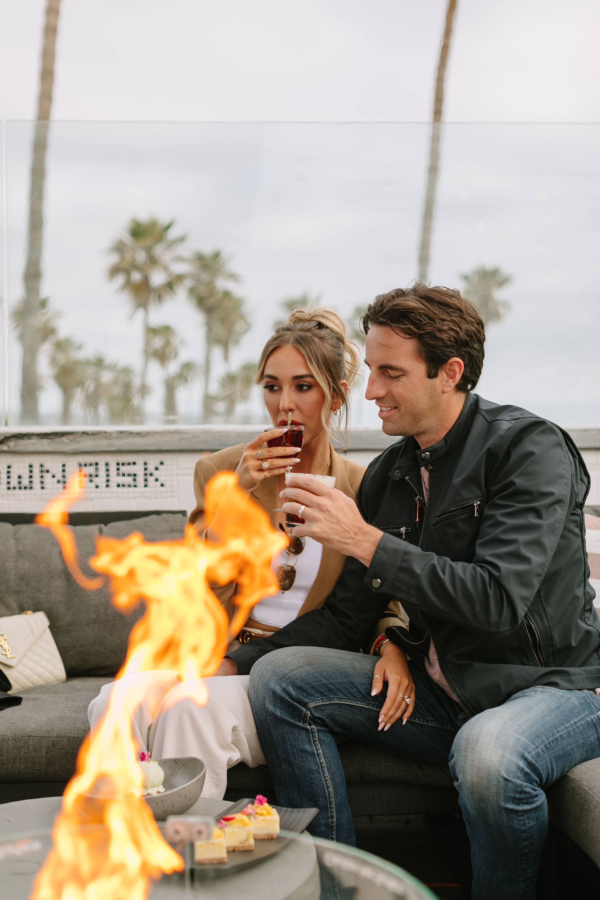 a man and woman sitting on a couch with a fire