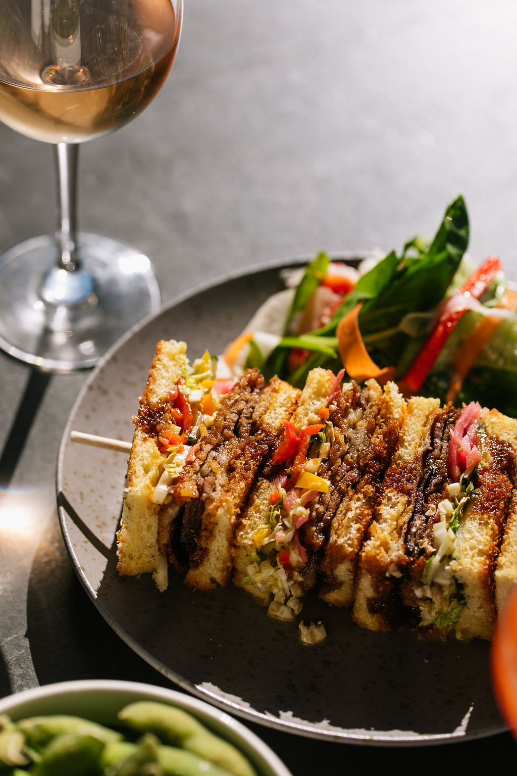 a plate of sandwiches and a glass of wine