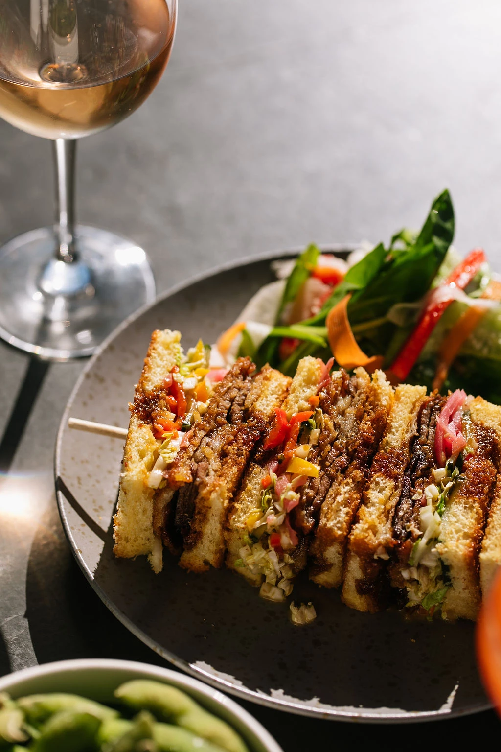 a plate of sandwiches and a glass of wine