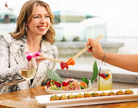 a woman holding chopsticks and a glass of wine