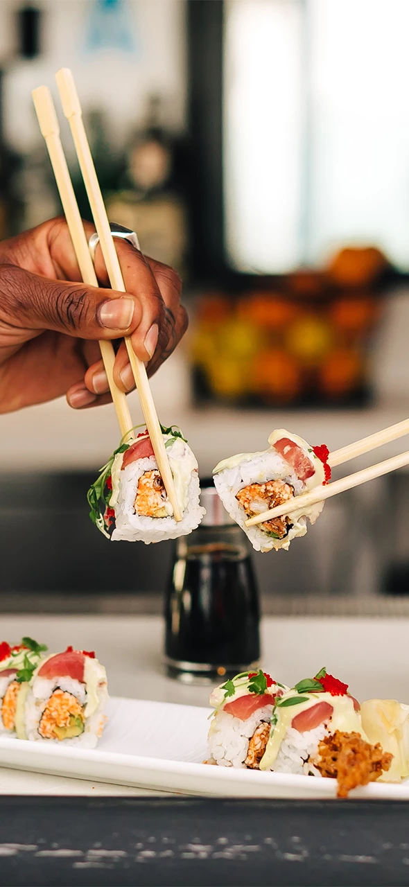 a person holding chopsticks with sushi