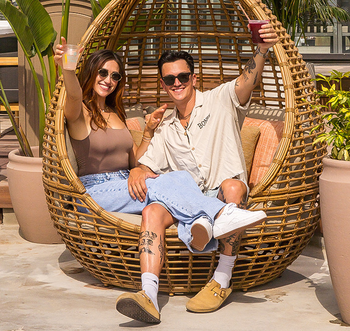 a man and woman sitting in a wicker chair