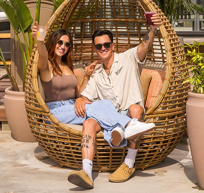 a man and woman sitting in a wicker chair
