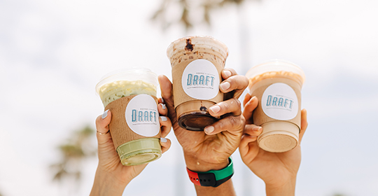 a group of hands holding cups of drinks