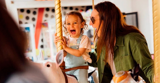 a woman and a child on a carousel