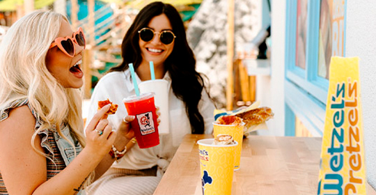 a woman holding drinks and a sandwich