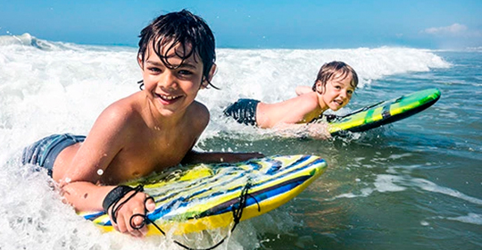 two boys on a body board in the water