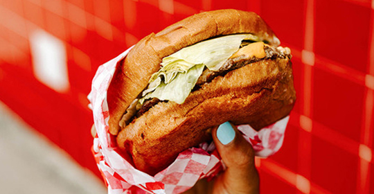 a hand holding a burger