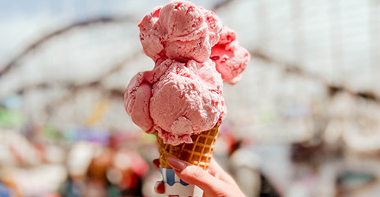 a hand holding a cone with a scoop of ice cream
