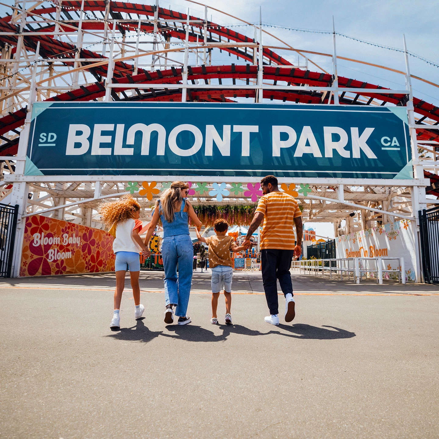 a group of people walking in front of a roller coaster