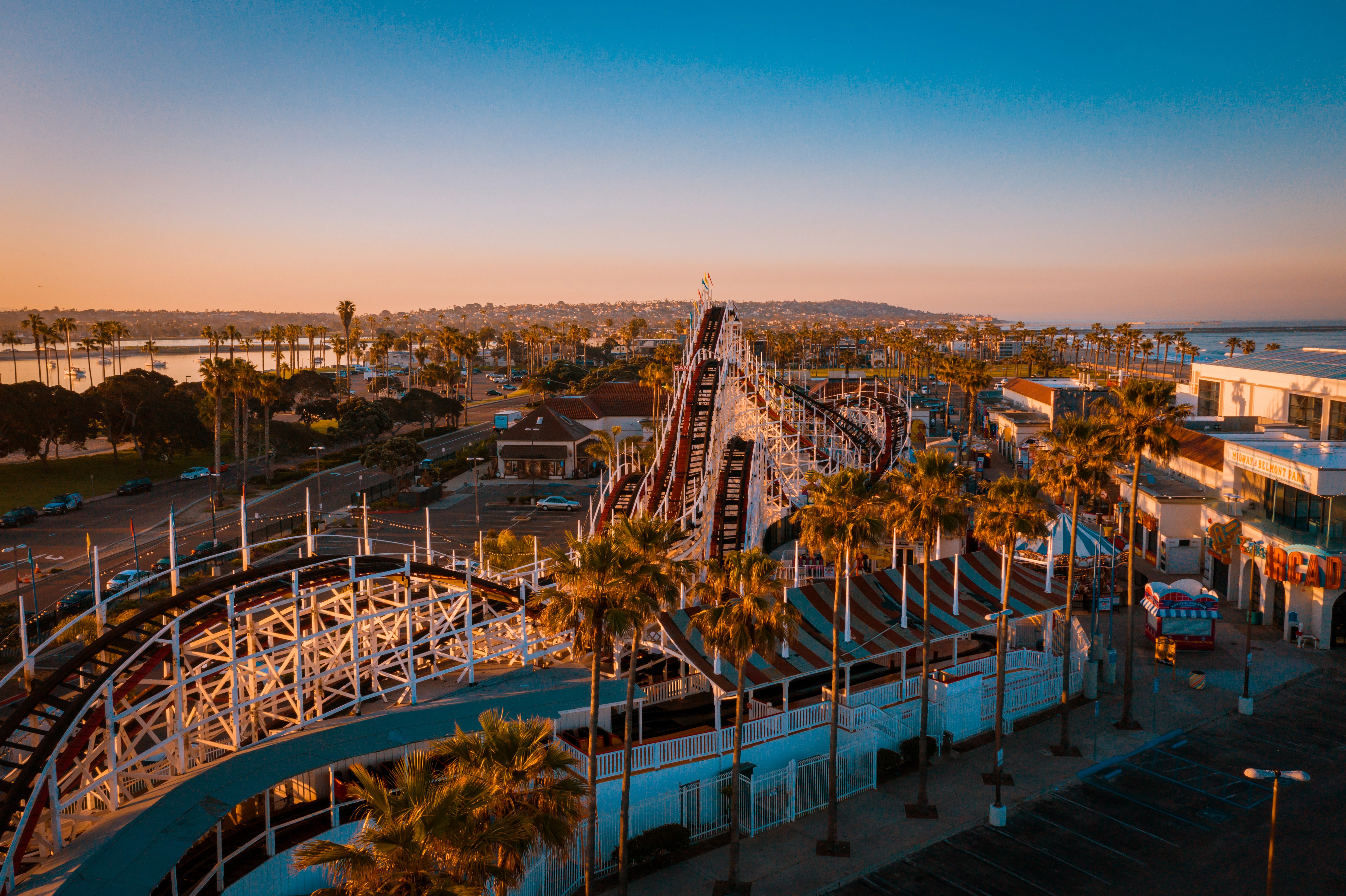 a roller coaster in a city at sunset
