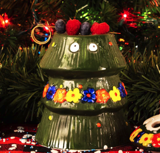 a green ceramic christmas tree with berries and flowers