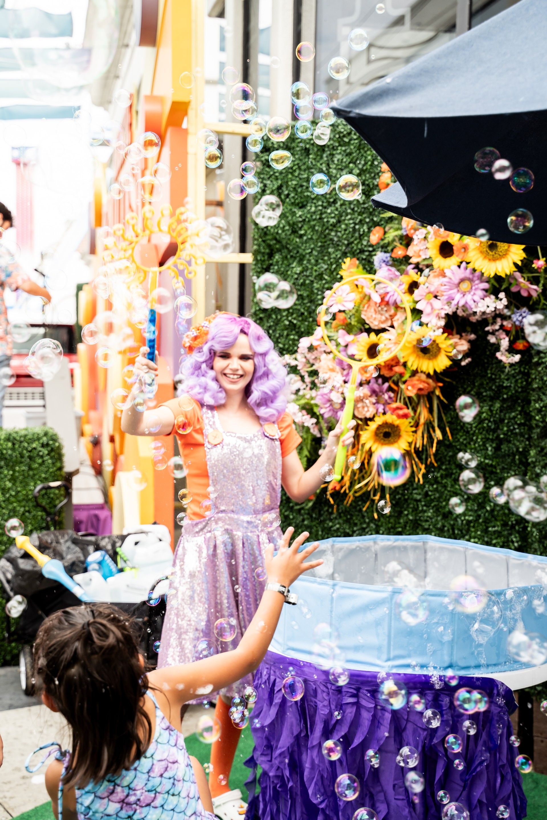 a girl in purple wig blowing bubbles