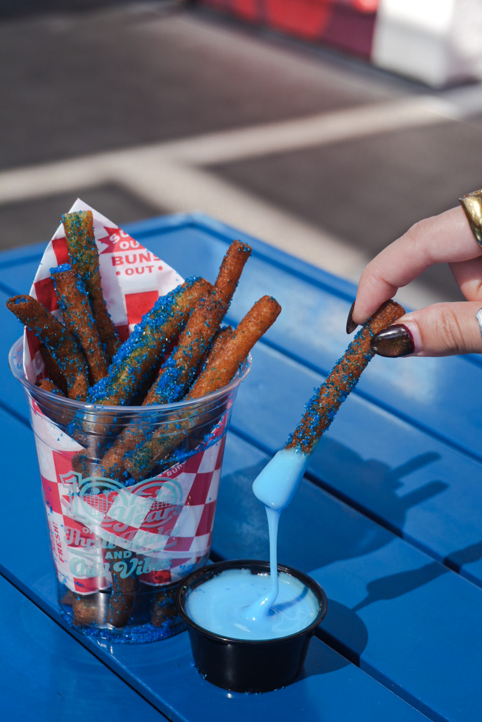 a hand dipping blue liquid into a cup of food