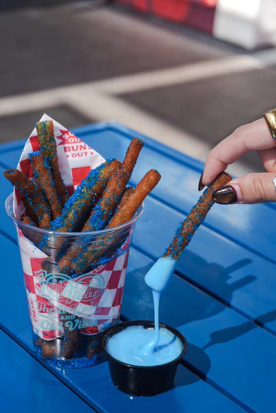 a hand dipping blue liquid into a cup of food