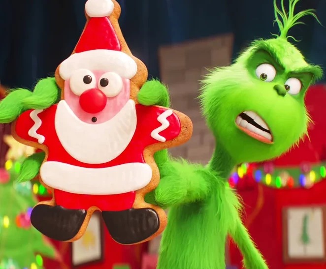 a green character holding a gingerbread cookie