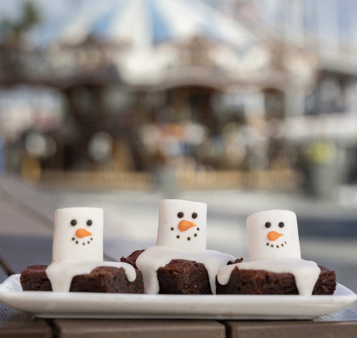 a plate of brownies with marshmallow snowman on top