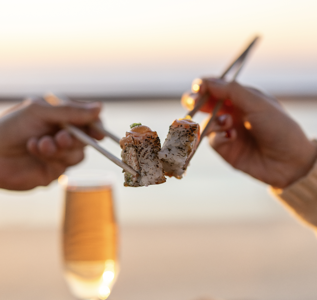a pair of hands holding chopsticks with meat