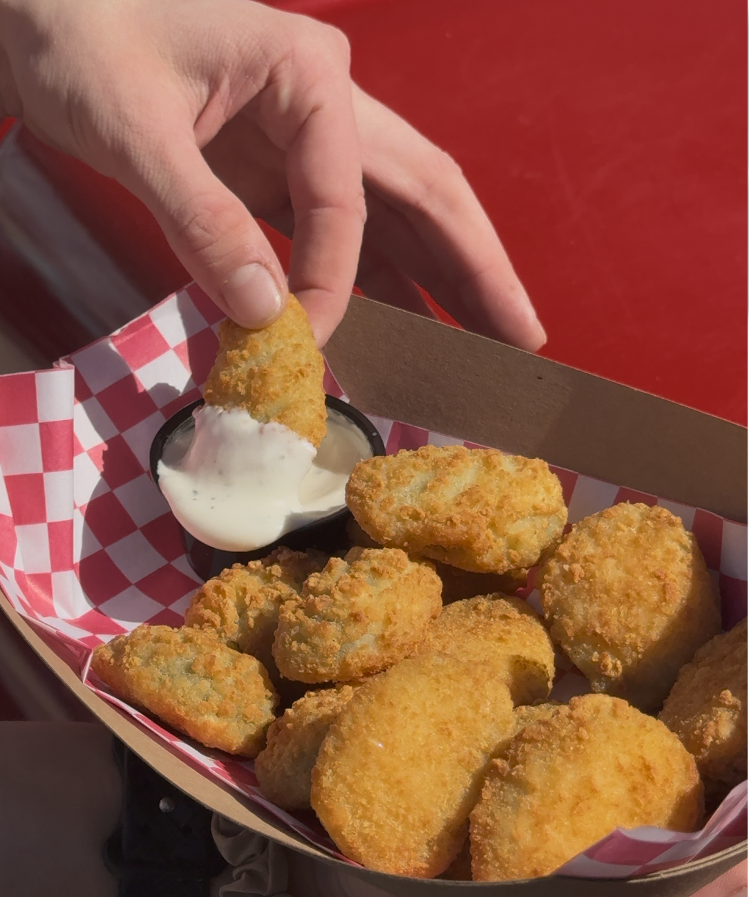 a hand dipping a piece of food into a container