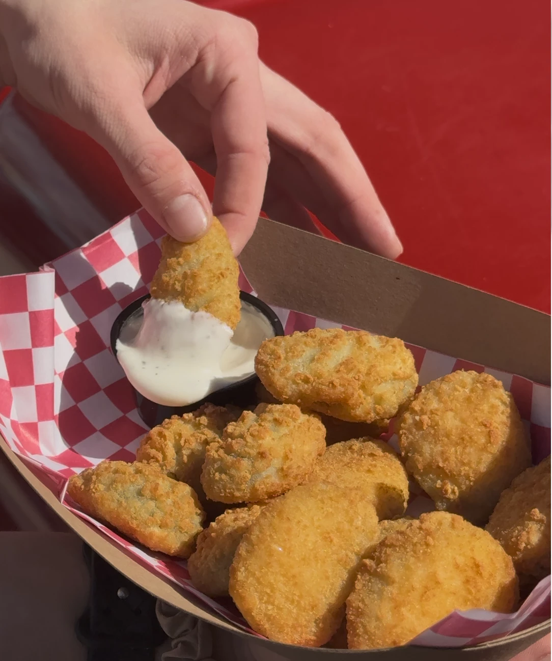 a hand dipping a piece of food into a container