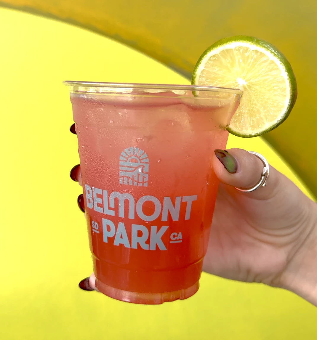 a hand holding a drink with a lime wedge