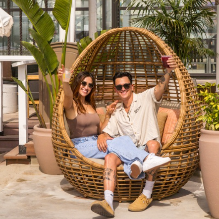 a man and woman sitting in a wicker chair
