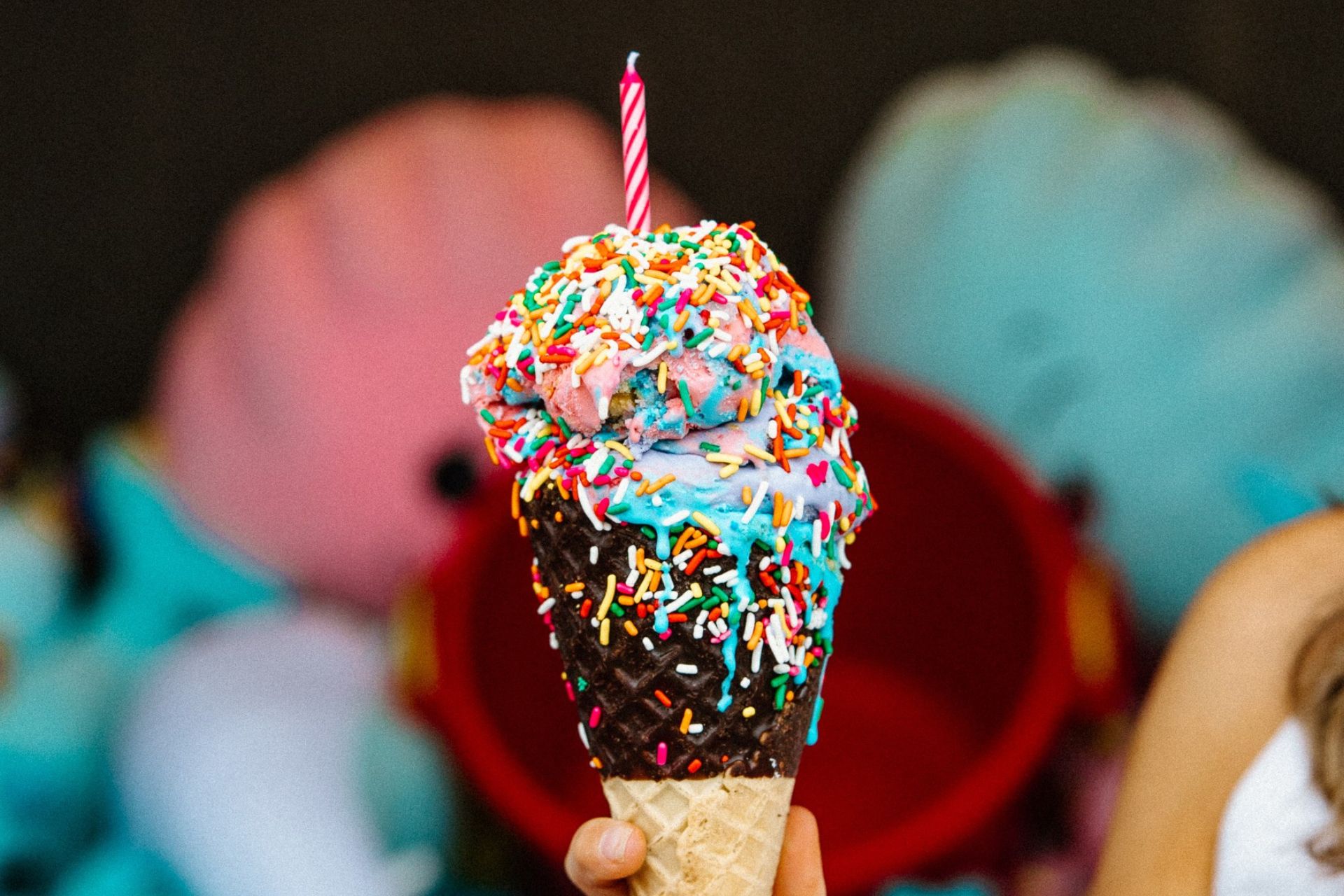 a hand holding an ice cream cone with a candle