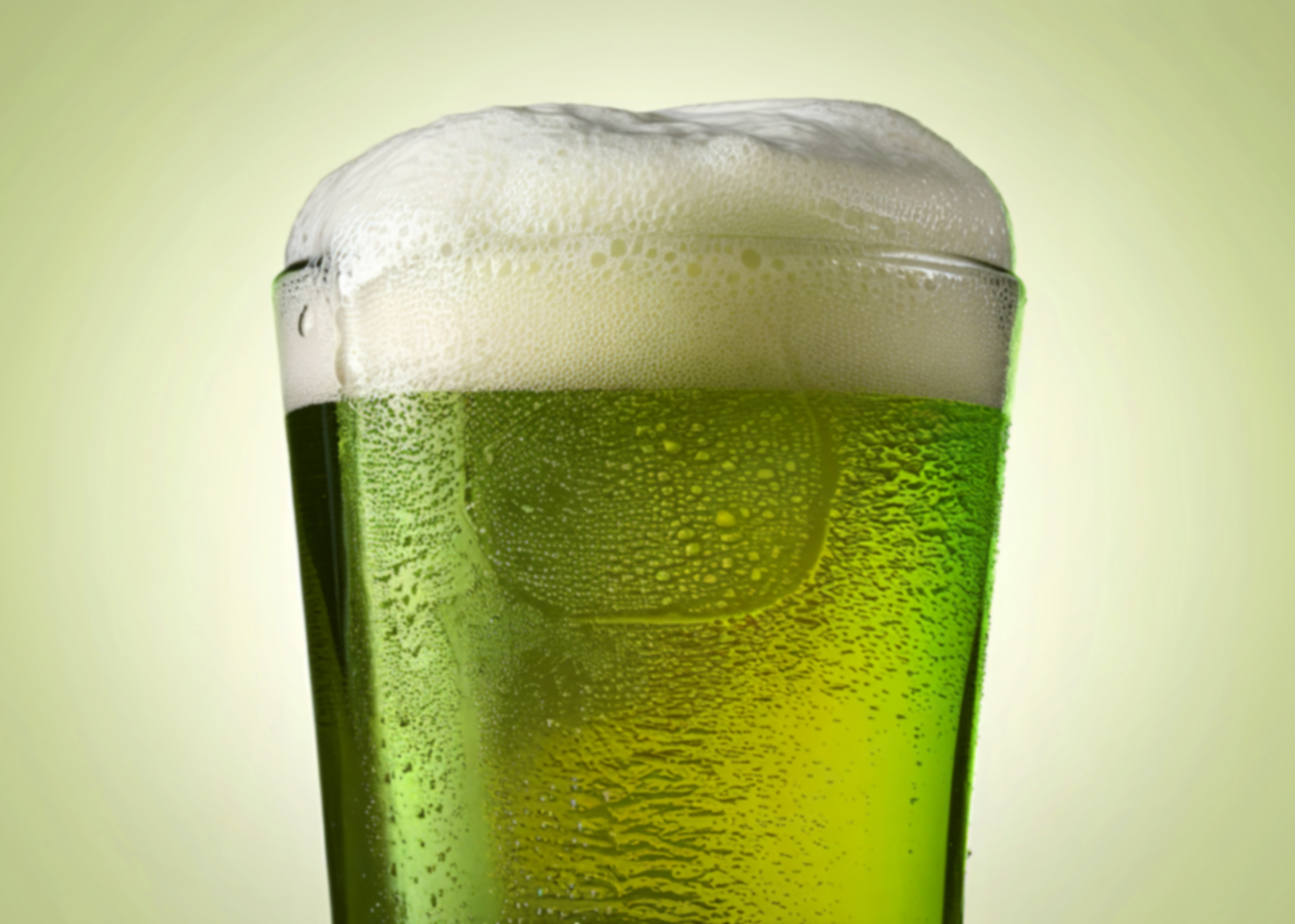 a glass of green beer with foam
