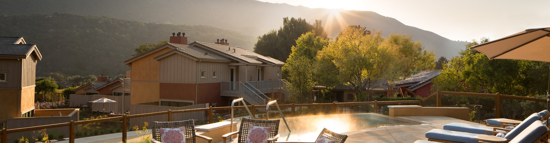a deck with chairs and a pool with trees and a house in the background