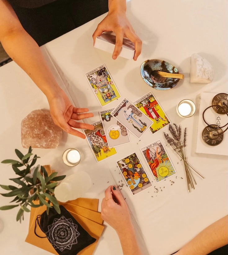a person's hands on a table with tarot cards