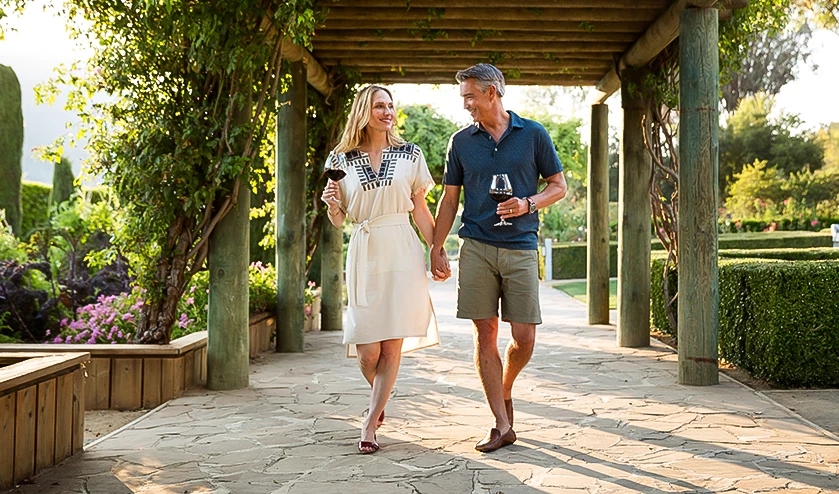 a man and woman holding hands and holding wine glasses