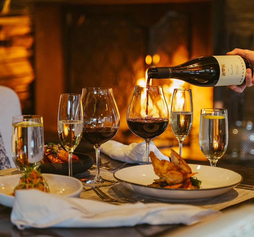 a person pouring wine into glasses