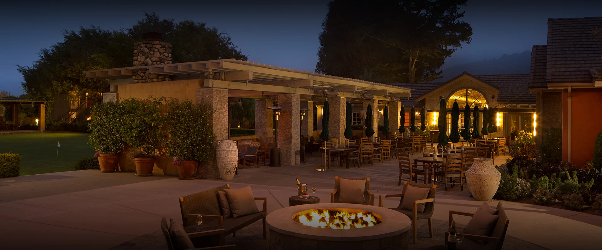a patio with tables and chairs and a fire pit