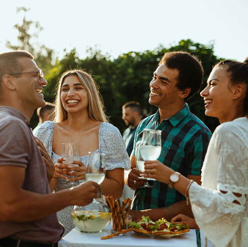 a group of people standing around a table with food and drinks