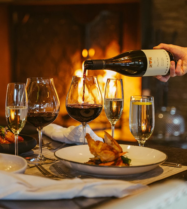 a person pouring wine into glasses
