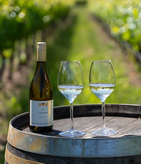 a bottle of wine and two wine glasses on a barrel