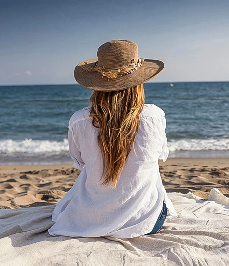 a woman sitting on a blanket at the beach
