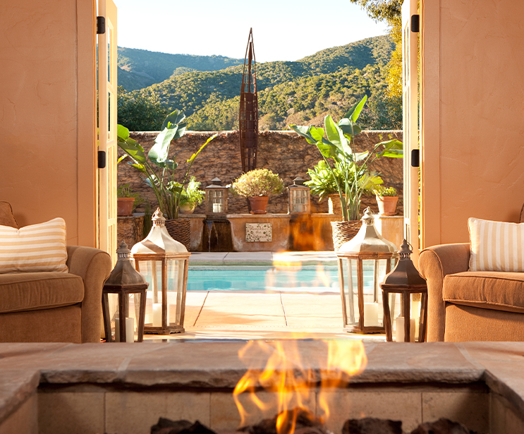 a fire in a pool with chairs and a fireplace
