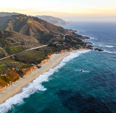 a beach with a road and a body of water