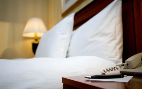 nightstand with a bed and lamp in background 