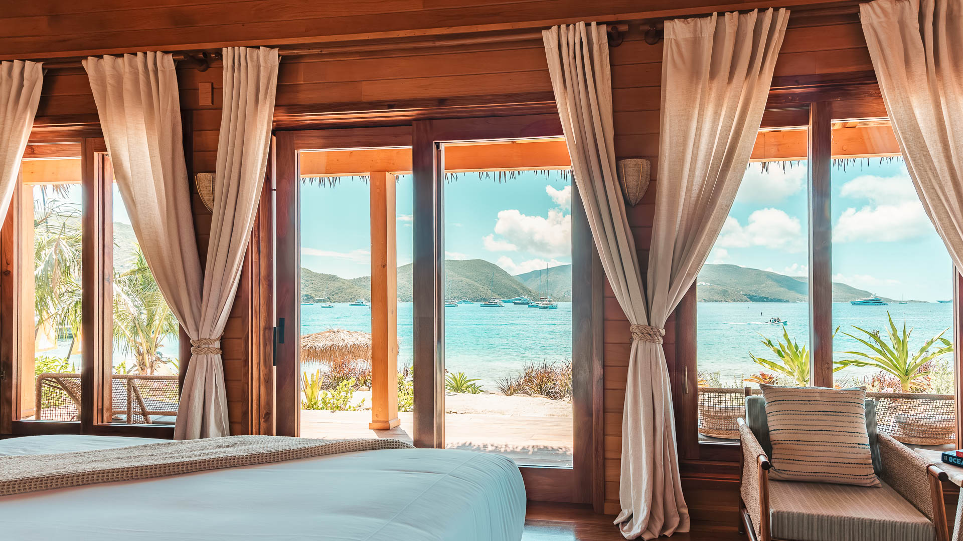a room with a bed and a view of the ocean through the windows