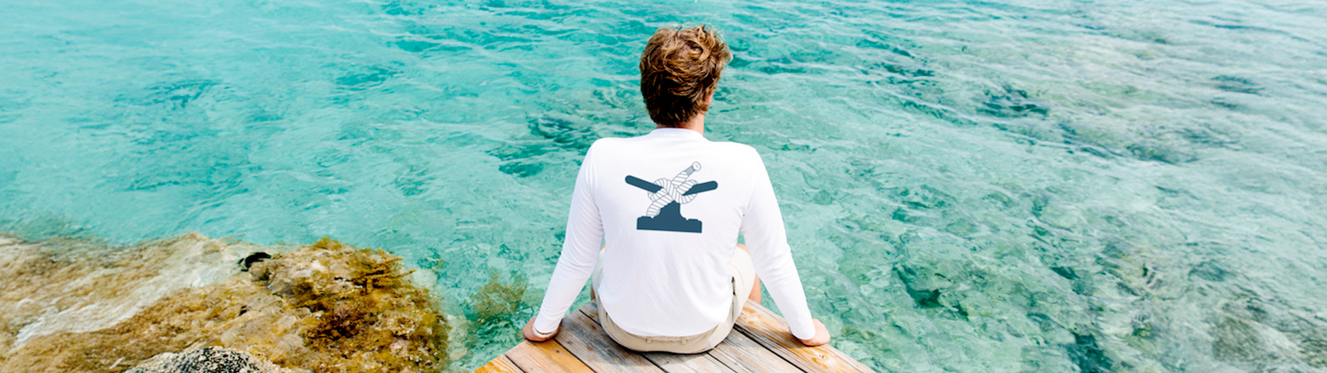 a man sitting on a dock with a boat on it